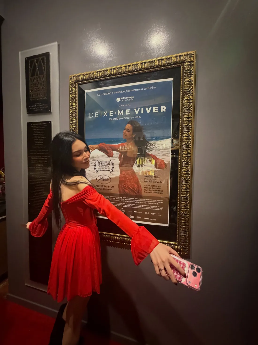 Cat Dantas beside the framed poster of Deixe-me Viver in Miami